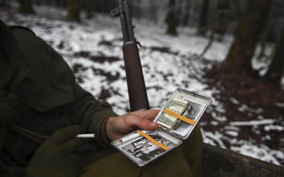 Wesley van Reen displays his authentic looking cigarette case complete with a family photo, a 40s pin-up girl and homemade 40s replica cigarettes on Dec. 14, 2014. He and other re-enactors portrayed the 106th Infantry Division, which fought in the Battle of the Bulge 70 years ago.