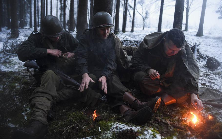 Dutch re-enactors, from left to right, Wesley van Reen, Rico Peters and Sjoerd Bijsterveld, warm up with small fires near their foxholes on Dec. 13, 2014. They were portraying the 106th Infantry Division, where it fought in the Battle of the Bulge in the heights above St. Vith, Belgium.