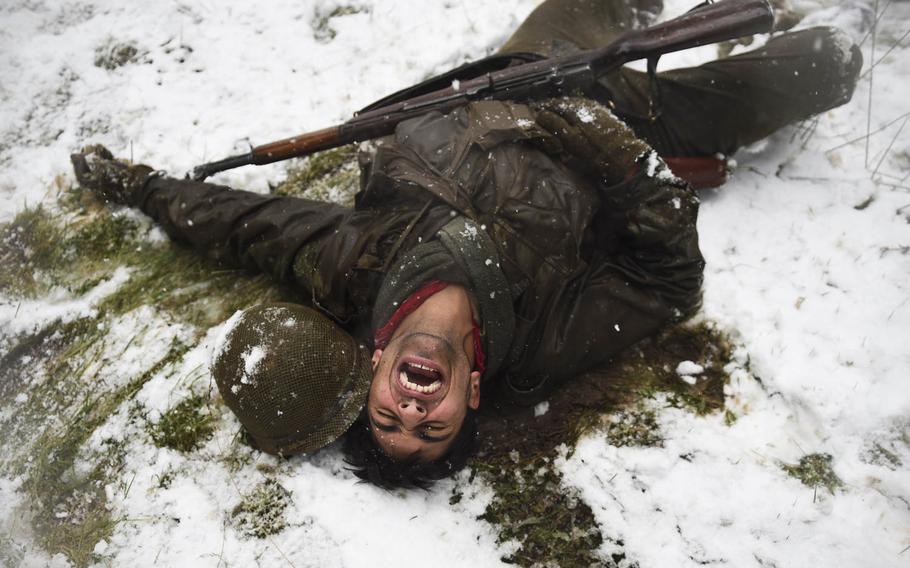 Mike Struik, portraying a wounded U.S. soldier in the 106th Infantry Division, lies in pain during a  Battle of the Bulge re-enactment on Dec. 13, 2014.
