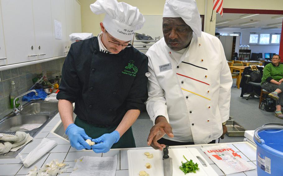 Chef D.L. West, a judge at this year's DODDS-Europe Culinary Faire, discusses preparation with Naples' Aaron Capps at Kaiserslautern High School on Feb. 25, 2015.