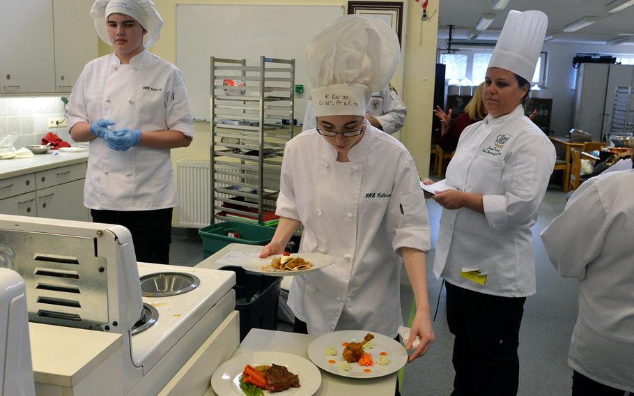 Jo Thibodeau of Vilseck's team No. 2 presents her team's dishes of Buffalo chicken with bleu cheese mousse, beef tenderloin with garlic parmesan risotto and apple pie tacos at the 2015 DODDS-Europe Culinary Faire held at Kaiserslautern High School, on Feb. 25, 2015.