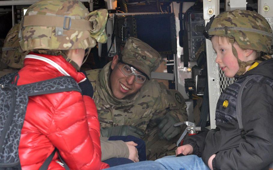 Pfc. Luis Diaz of Iron Troop, 3rd Squadron, 2nd Cavalry Regiment talks to two children decked out in U.S. Army helmets during a static display of the unit's Strykers in Panevezys, Lithuania, Monday, March 23, 2015. The soldiers of Iron Troop made a stop in downtown Panevezys during their convoy back to their home base in Vilseck, Germany, as part of the so-called Dragoon Ride, after training in Estonia.