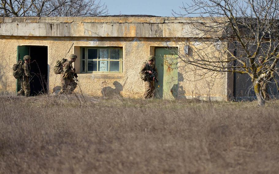 Soldiers of the 173rd Airborne Brigade clear a house after parachuting into the Smardan training center, Romania, Tuesday, March 24, 2015.