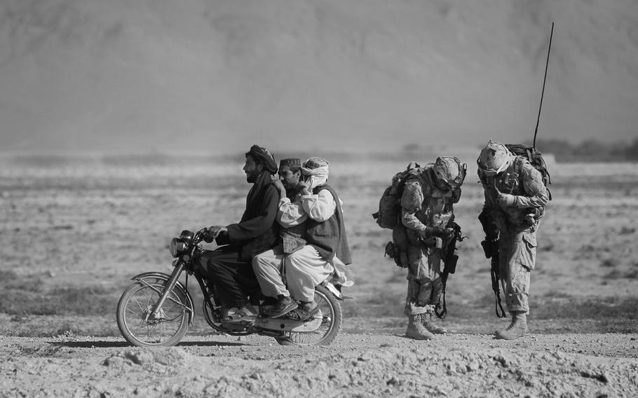 Afghan men on a moto bike overtake Canadian soldiers of the Royal Canadian Regiment on patrol in the district of Panjwai, southwest of Kandahar, Afghanistan.