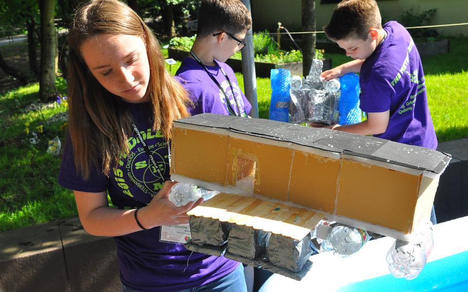 Morgan Houchins, a seventh-grader at Ramstein Middle School, holds up the  houseboat prototype she made with plastic bottles, wood, Styrofoam and other materials during the middle school STEMposium on Thursday, May 14, 2015, at Ramstein Air Base, Germany.