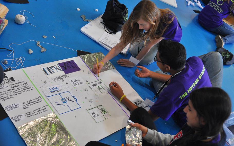 Briget Lilleman, far left, Elijah Tross and Alaina Schwartz work on their three-part poster board during the middle school STEMposium on Thursday, May 14, 2015, at Ramstein Air Base, Germany.