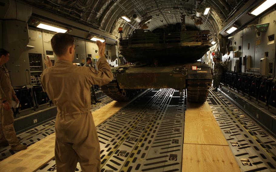 An Air Force crew chief directs and M1A2 Abrams tank into  a C-17 transport plane at Ramstein Air Base in Germanyon  Saturday, June 20, 2015. The tank is one of two headed to Bulgaria for a live-fire exercise next week.