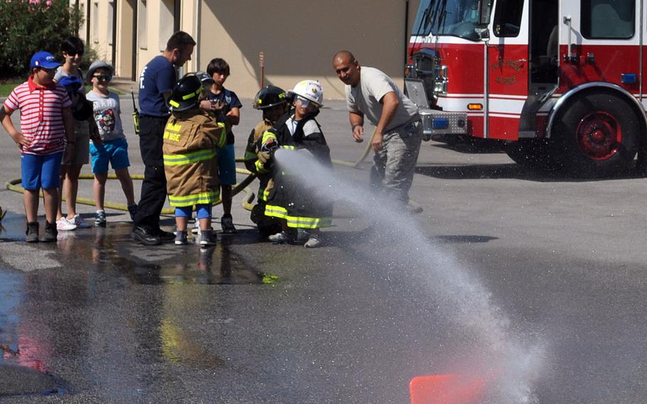 A group of Italian children from Porcia, Italy, watch as a one of them strikes down a cone at Aviano Air Base's fire department on Friday, July 10, 2015.