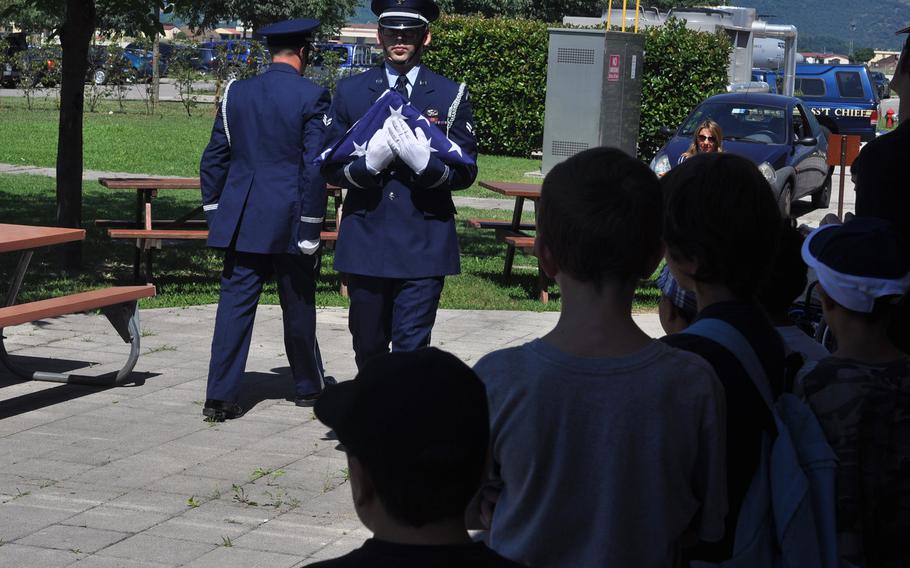 Airman 1st Class Roger Lanoie and fellow 31st Fighter Wing Honor Guard member Senior Airman Joshua Sharer give a flag-folding demonstration to a group visiting Aviano Air Base, Italy on Friday, July 10, 2015.