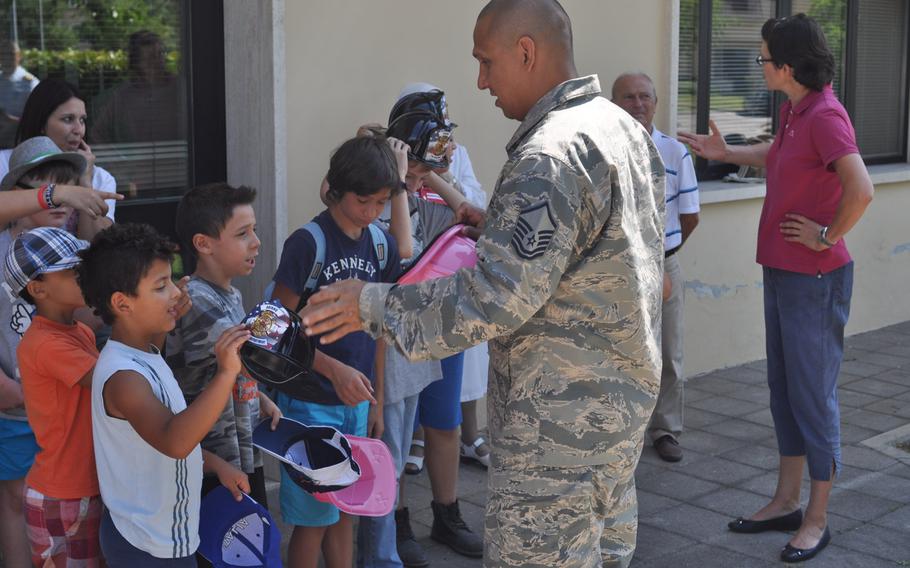 Master Sgt. Angus Adolpho, Aviano assistant fire chief, hands out fire engine hats to children from Porcia, Italy, during a tour of Aviano Air Base's fire department, Friday, July 10, 2015.