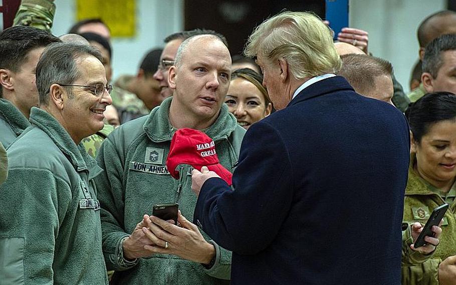 President Donald Trump autographs a hat at Ramstein Air Base, Germany, Thursday, Dec. 27, 2018.