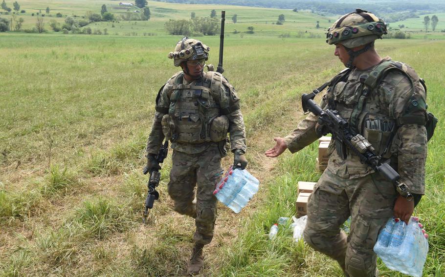 Soldiers with the Army's 2nd Cavalry Regiment bring water to their fellow Dragoons during Exercise Saber Guardian in Cincu, Romania, Monday, June 17, 2019.