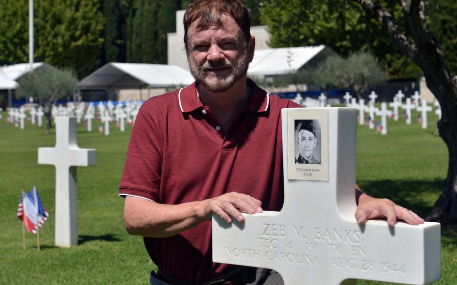 Steven Hill poses next to the grave of his uncle, Tech. 4 Zeb Murphy Banks, at Rhone American Cemetery in Draguignan, France, Thursday, Aug. 15, 2019. Banks was an Army tanker who was killed Aug. 28, 1944, when his tank hit a mine. Hill came to the cemetery to attend Friday's ceremony marking the 75th anniversary of Operation Dragoon.