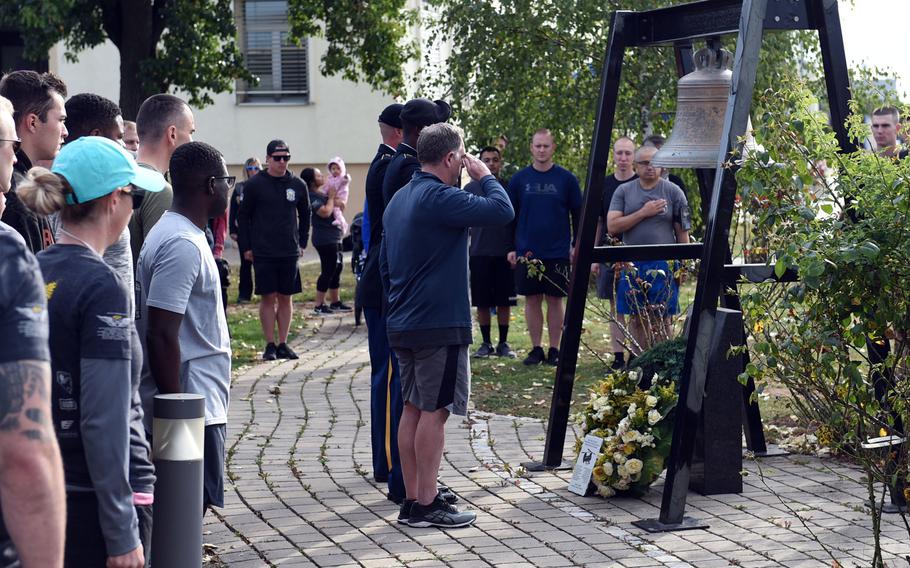 The former commander of the "Big Windy," Craig Wilhelm, center, salutes the memorial to the crew of the Windy 25 flight at Ansbach, Germany, on Sept. 6, 2019, as soldiers with the Army's 12th Combat Aviation Brigade stand at attention during the playing of taps, before the Windy 25 5K race. 