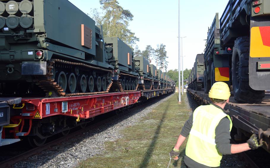 A railyard worker walks past a  row of M270-A1 MLRS rocket launch systems that arrived in Grafenwoehr, Germany, Wednesday, Sept. 11, 2019.