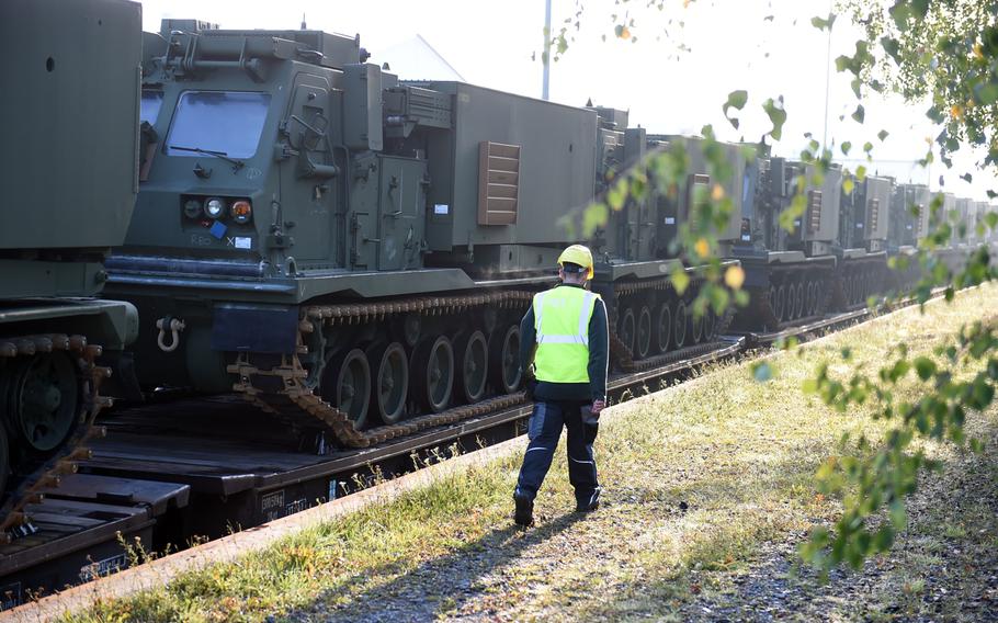 A railyard worker walks past a  row of M270-A1 MLRS rocket launch systems that arrivied on a train in Grafenwoehr, Germany, Wednesday, Sept. 11, 2019.