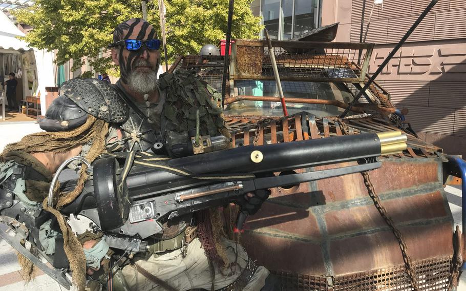Dressed as a post-apocalyptic warrior, Brian Sachs, 54, poses for a photo in front of his ''Mad Max: Fury Road''-inspired automobile in front of the Ramstein main exchange on Sunday, Sept.22, 2019. Sachs helped organize the mall's KMCC Comic Con event to celebrate the shopping center's 10-year anniversary and the opening of a new comic shop.