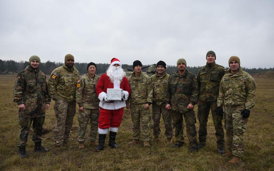German soldiers, U.S. soldiers from the 4-319th Field Artillery Regiment and Santa Claus pose at the Grafenwoehr Training Area, Germany, on Dec. 12, 2019. Soldiers marched to deliver toys from a drop zone to Tower Barracks for children through Haus St. Elisabeth in Windischeschenbach, Germany.