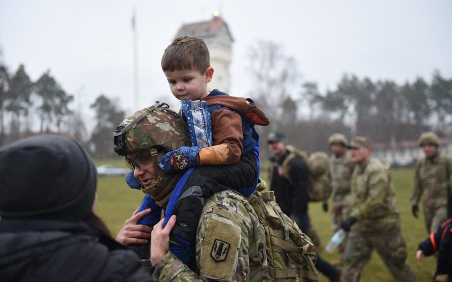 Maj. Jason Byers, left, the chaplain with the 41st Field Artillery Brigade, carries his son, Lincoln Byers, to the end of a march at Grafenwoehr, Germany, on Dec. 12, 2019. Soldiers marched to deliver toys from a drop zone to Tower Barracks to a German home for children.