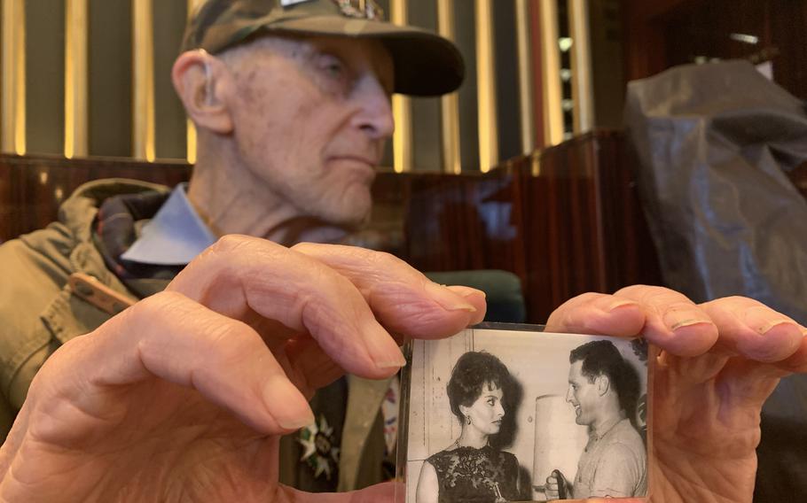 In a Parisian cafe on Friday, Feb. 14, 2020, Stephen Weiss, 94, shows off a photo of himself with Italian actress Sophia Loren during his early post-World War II career in Hollywood. Weiss, a war and trauma researcher based in London, battled post-traumatic stress disorder after the war, but credits therapy with helping him turn his life around and lead three successful careers in his long life.