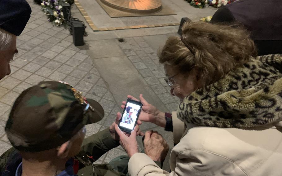 A French woman shows American World War II veteran Stephen Weiss a photo she took of him at France's Tomb of the Unknown Soldier during a twilight ceremony under the Arc de Triomphe on Friday, Feb. 14, 2020.