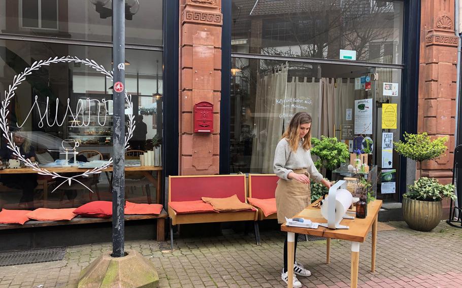 Dylan Page stands outside Cafe Susann in Kaiserslautern, Germany selling cakes to passing customers on Tuesday, March 17, 2020. Restaurants in Kaiserslautern are partially exempted from federal and local restrictions aimed at stemming the spread of the coronavirus in Germany.