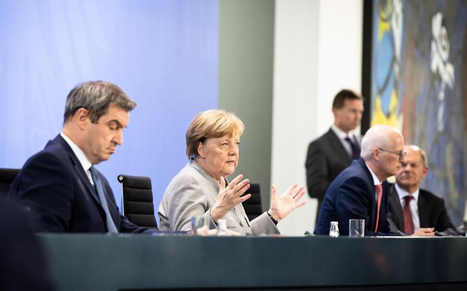 German Chancellor Angela Merkel, second from left, answers questions from reporters in Berlin, April 15, 2020. Seated with her are Bavarian Minister President Markus Soeder, left, Lord Mayor Peter Tschentscher of Hamburg, and German Finance Minister Olaf Scholz, right, as they discuss the country's extension of measures taken in the wake of the coronavirus pandemic.