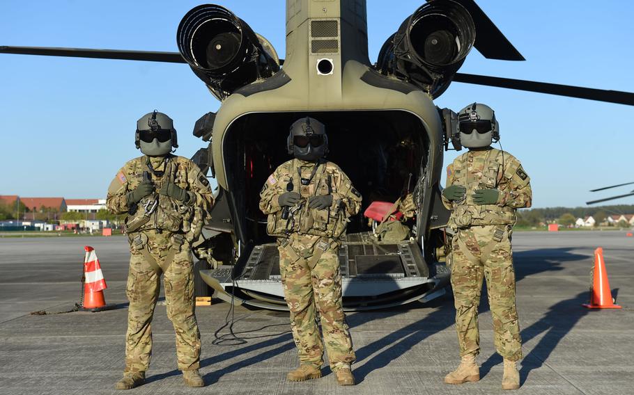 From left, Sgt. Matthew Cullen, a flight engineer, Staff Sgt. Elijah Joice, a flight engineer instructor, and Chief Warrant Officer 2 Dylan Hawkins, an aviator, all with the 12th Combat Aviation Brigade, stand in front of a CH-47 Chinook helicopter before a pilot progression training exercise on Ansbach, Germany, April 20, 2020. The training went ahead, with modifications, in spite of the coronavirus pandemic.