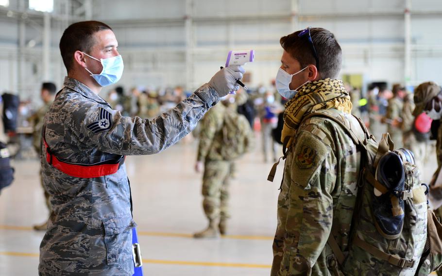 An 31st Medical Group airman takes the temperature of an airman returning from deployment, as part of a coronavirus screening, at Aviano Air Base, Italy, April 18, 2020.