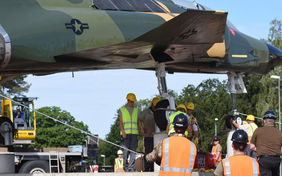 Personnel at Ramstein Air Base, Germany, help secure the wheels of a refurbished F-4 Phantom fighter jet on concrete pedestals by the northside gym, where the aircraft is on static display, June 8, 2020.