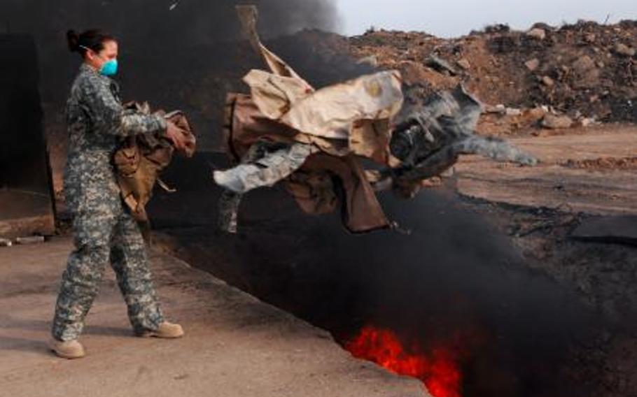 Senior Airman Frances Gavalis tosses unserviceable uniform items into a burn pit in Iraq in 2008. 