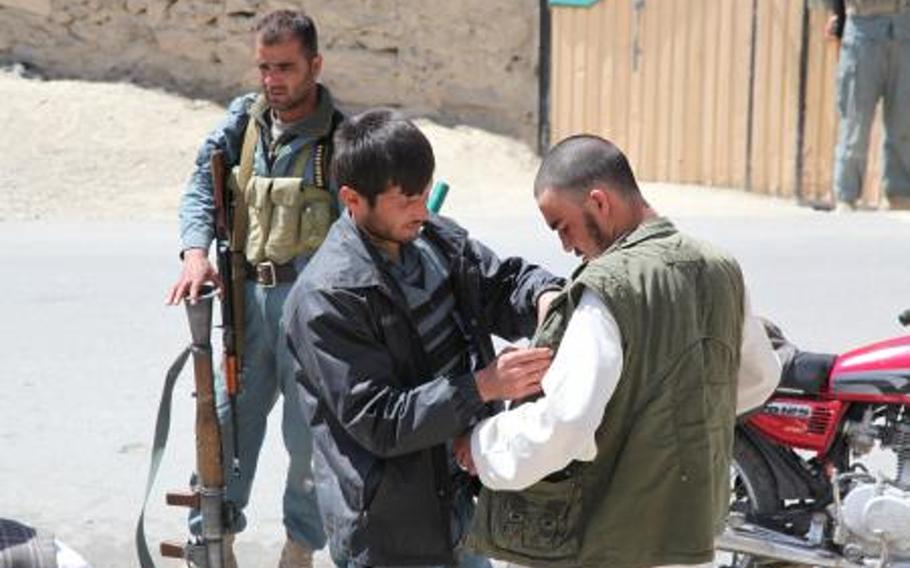An Afghan National Policeman searches a villager while on patrol in Sayed Abad District, Wardak province, in April 2011. Twin suicide bombings near Combat Outpost Sayed Abad in eastern Afghanistan Saturday killed at least seven and injuring dozens. No Americans were reported killed or injured.  