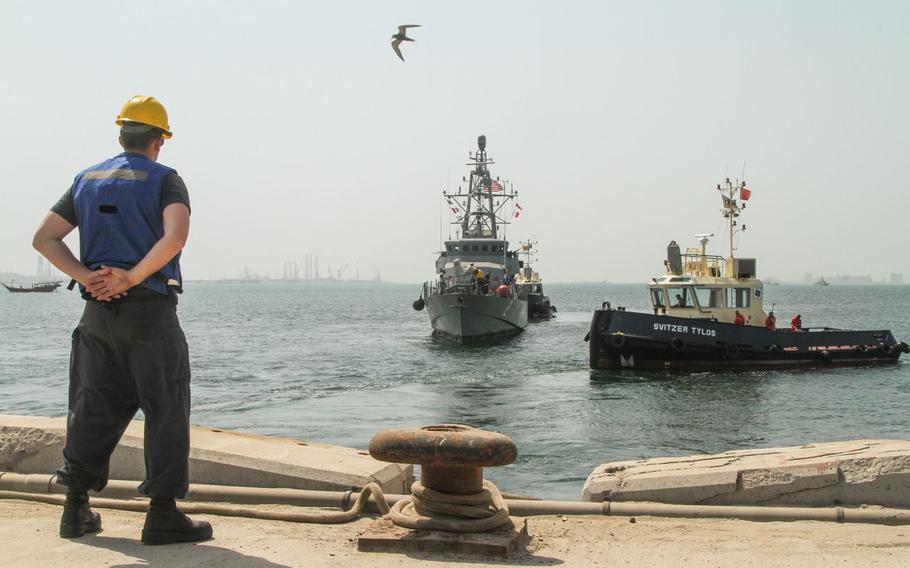 A line handler waits on the pier as tug boats position the USS Tempest to go pier-side in Bahrain for the first time.