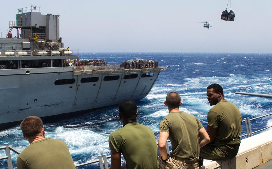 U.S. Marines assigned to the 26th Marine Expeditionary Unit sit on the flight deck before a Navy MH-60S Seahawk helicopter transports food and supplies to the USS San Antonio (LPD 17), during a resupply at sea, July 9, 2013. The 26th MEU is a Marine Air-Ground Task Force forward deployed to the U.S. 5th Fleet area of responsibility aboard the Kearsarge Amphibious Ready Group.