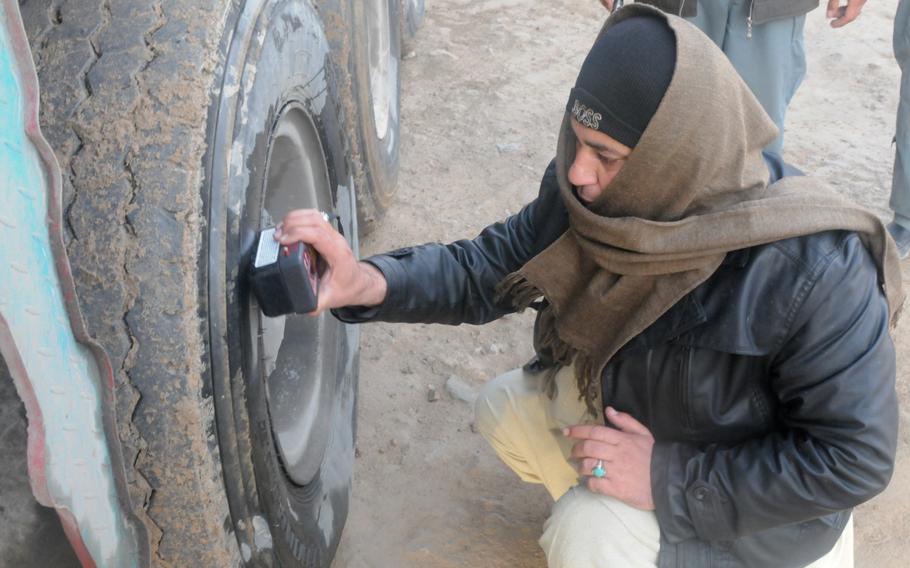 An Afghan Customs Directorate agent scans a truck tire for abnormality during operations outside of Kandahar City, Afghanistan. Working alongside American forces, Afghan National Security Forces conducted searches of trucks for contraband and ensured drivers had the proper paperwork to operating on Kandahar’s roads in January 2012.