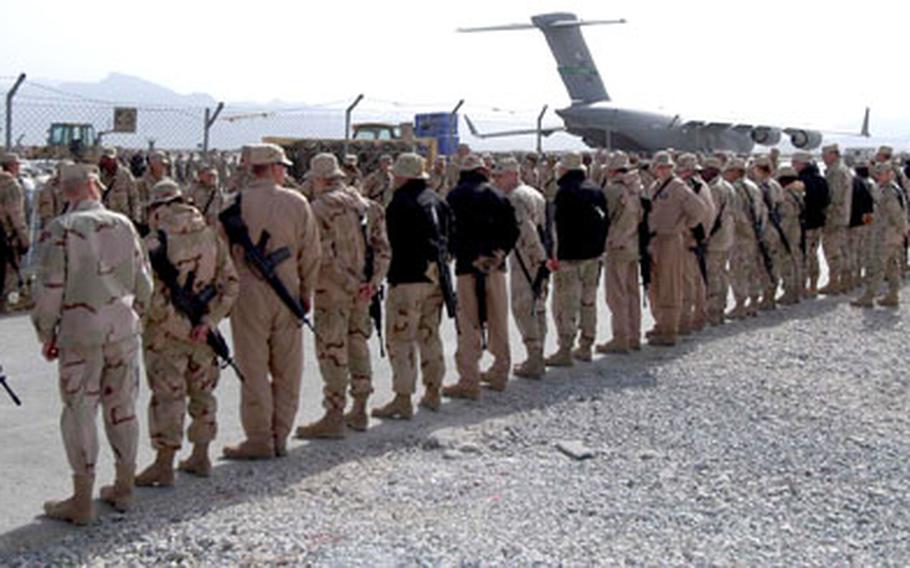 Servicemembers and civilians line the road to the Bagram Air Base flight line as they wait for a procession of Humvees carrying the coffins of 18 victims of a helicopter crash near Ghazni, Afghanistan, in 2005. A similar ceremony was held early August 12, 2013, for three Americans killed in eastern Afghanistan.