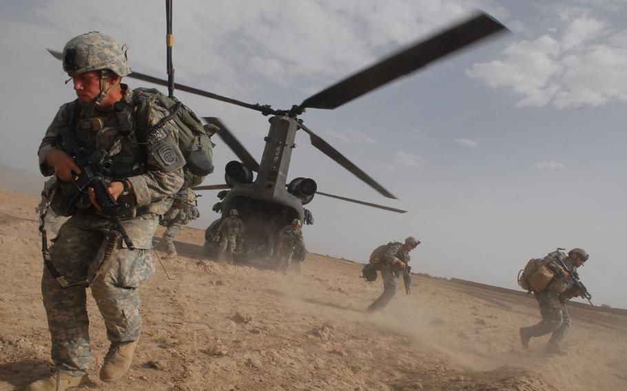 Spc. Colin Hankinson, 20, of Richardson, Texas, left foreground, hustles from the belly of a Chinook helicopter during a recent air assault in Zabul Province, Afghanistan.