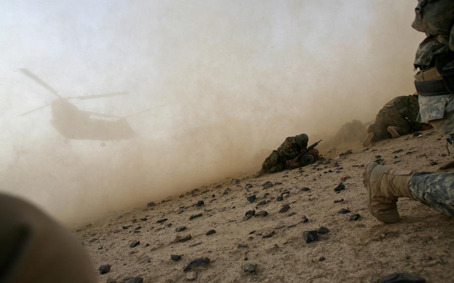 U.S. soldiers with Company C, 2nd Battalion, 508th Parachute Infantry Regiment and Afghan troops hug the ground as a CH-47 Chinook helicopter kicks up dust and rocks. It was lifting off outside the village of Shuyene Wusa, as part of a recent clearing operation in the Arghandab River valley, Kandahar province, Afghanistan. 