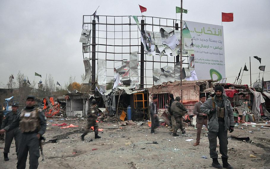 Afghan security forces stand guard near shops damaged in a suicide car bomb attack Saturday, Nov. 16, 2013, in Kabul near the site of a government-sponsored conference of elders convening Thursday to discuss a security pact that will determine whether U.S. troops stay in Afghanistan past 2014.