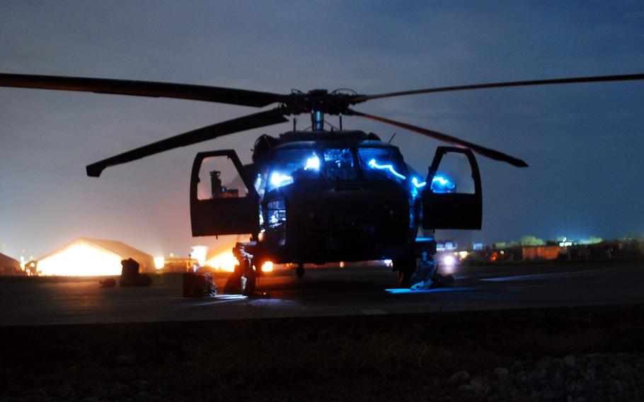 Light emanates from a UH-60M Black Hawk while crew members inspect the helicopter before launching in Afghanistan on Dec. 8, 2013.