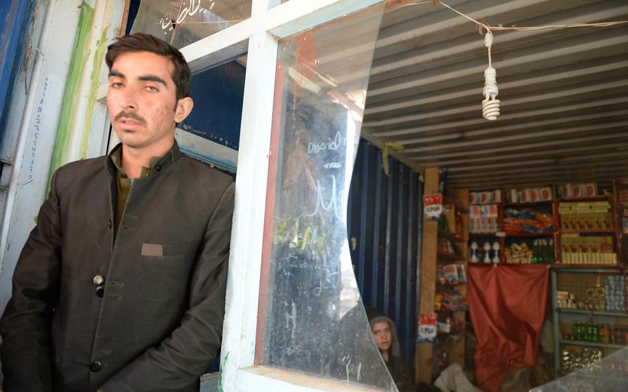 A shopkeeper stands by a window that was shattered by a suicide car bombing in Kabul Monday, Feb. 10, 2014, that killed at least two foreign contractors working for the NATO-led International Security Assistance force.