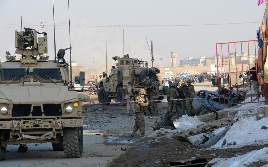 Troops with the International Security Assistance Force secure the scene of a suicide bombing in Kabul that killed at least two foreign contractors working for the NATO-led coalition.  The blast on Monday, Feb. 10, 2014, scattered pieces of vehicles for hundreds of yards.