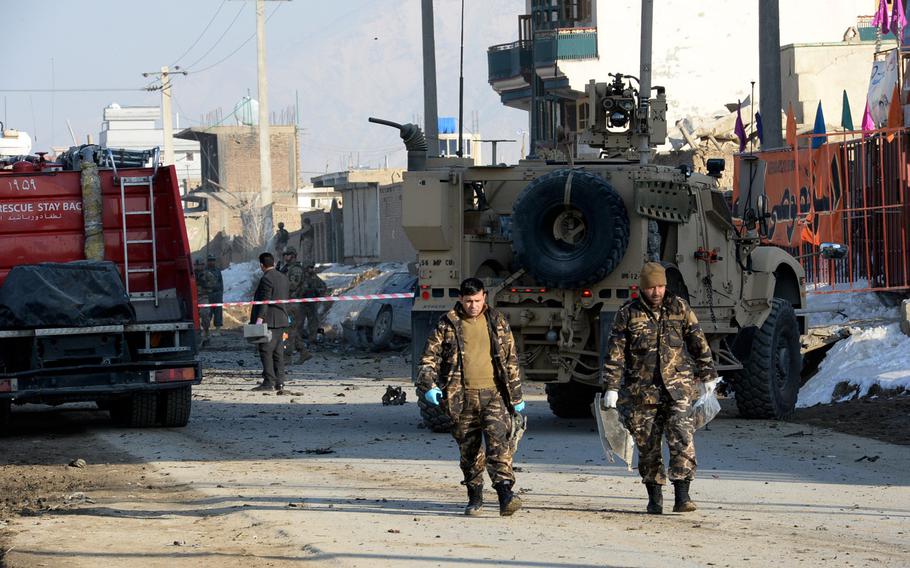 Afghan government investigators remove evidence from the scene of a suicide bombing in Kabul on Monday, Feb. 10, 2014. The blast killed at least two foreign contractors working for the NATO-led International Security Assistance force.