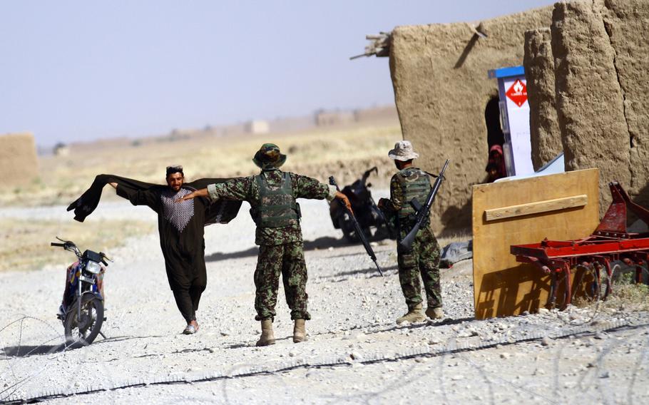 An Afghan National Army solider tells a local Afghan to put his arms out for a personnel search at a vehicle checkpoint in May 2013.