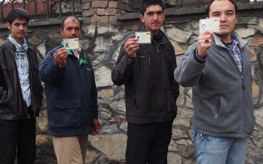 Afghans show off their voter registration cards in Kabul on Saturday, April 5, 2014, while waiting in line to vote in the country's presidential election. Despite rainy weather and threats of violence, there were long lines at polling stations in the capital. 