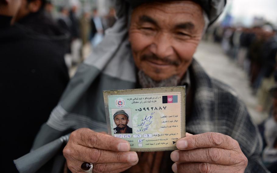 Kabul resident Gul Mohammed displays his voter registration card before voting at a mosque in Kabul during the national elections on Saturday, April 5, 2014.