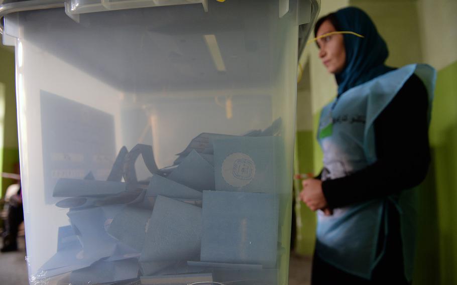 An Afghan election worker stands by ballot boxes just before the polls closed on Saturday, April 5, 2014. Afghans formed lines for blocks to wait for their chance to cast a vote in the presidential election.