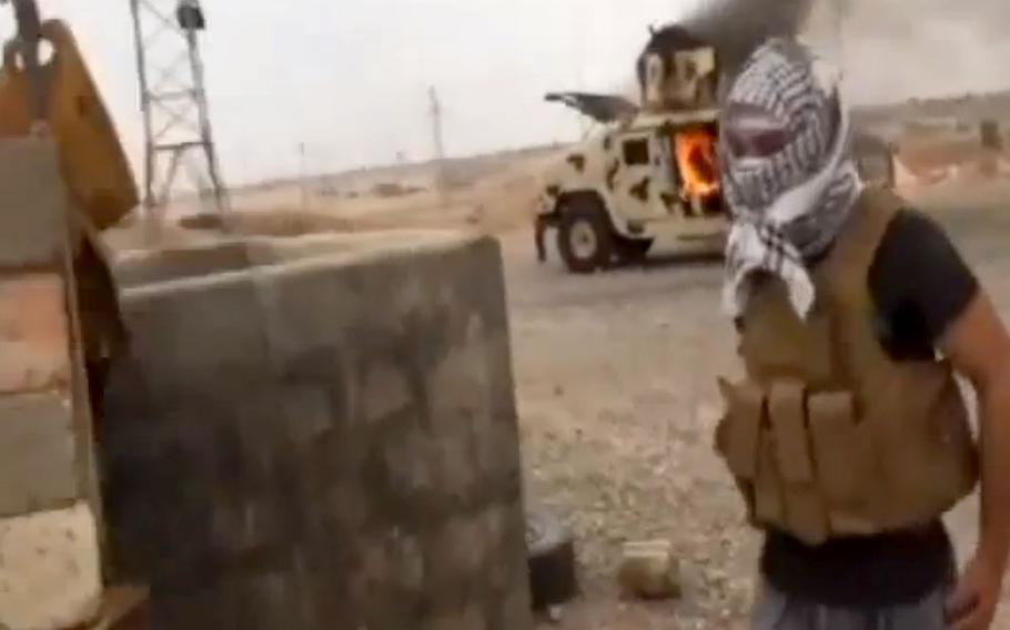 This image made from video posted by Iraqi0Revolution, a group supporting the al-Qaida breakaway Islamic State of Iraq and the Levant (ISIL) on Wednesday, June 11, 2014, which has been verified and is consistent with other AP reporting, shows a militant standing in front of a burning Iraqi Army Humvee in Tikrit, Iraq. 