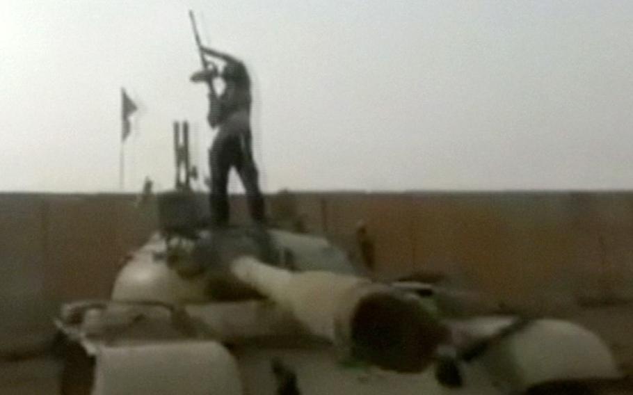 A militant stands on top of a tank at a military compound abandoned by the Iraqi military near Tikrit in Salah al-Din province, Iraq, in this image from video taken by militants Wednesday, June 11, 2014, which has been authenticated based on its contents and other AP reporting.