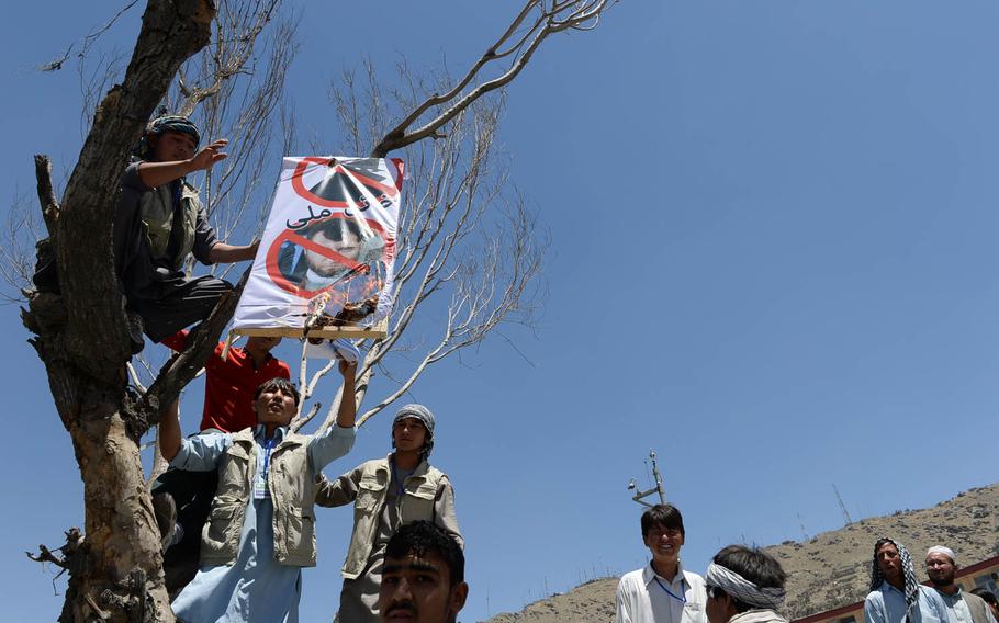 Protesters set alight a picture of an official with the Independent Election Commission, Afghanistan's main election body, at a rally Saturday, June 21, 2014, in Kabul. Supporters of presidential candidate Abdullah Abdullah are angry over what they see as massive fraud in the country's June 14 presidential election runoff.